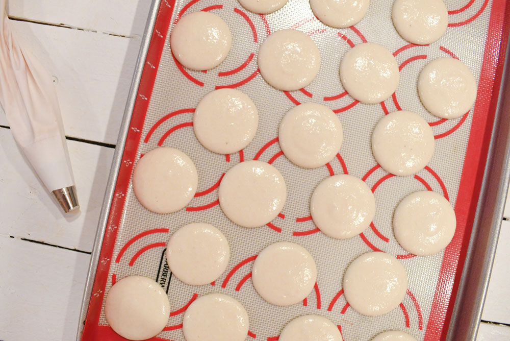 Perfect homemade macarons piped onto silicone baking mat