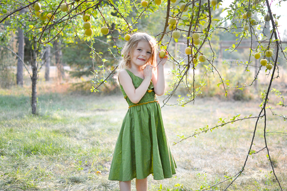 little girl picking apples green dress