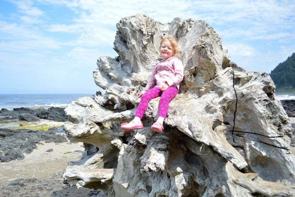 Oregon Coast visit with kids girl sitting on driftwood